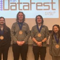 Four students awarded the Best Use of External Data Award pose in front of the DataFest logo.